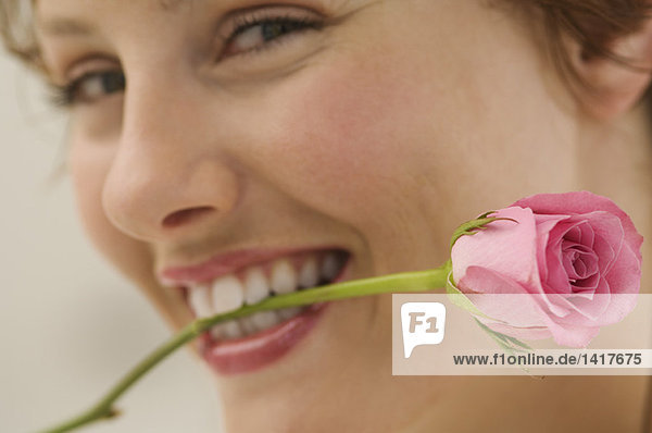 Porträt einer jungen Frau mit Rose zwischen den Zähnen