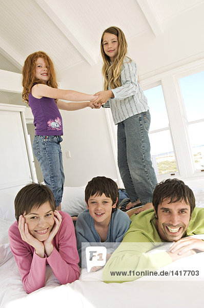 Smiling couple and three children on bed