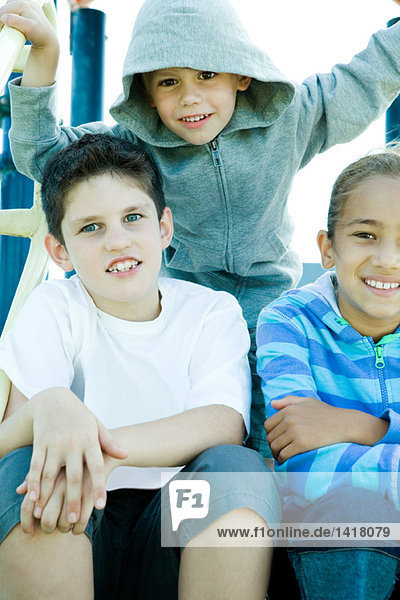 Kinder auf Spielgeräten  lächelnd vor der Kamera