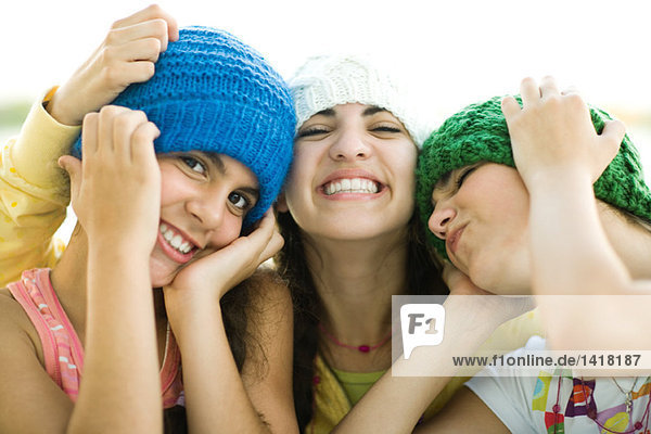Three young female friends wearing knit hats  smiling