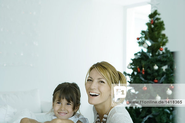 Frau und Tochter vor dem Weihnachtsbaum