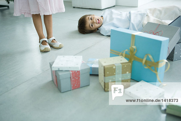 Junge auf dem Boden neben Geschenken liegend