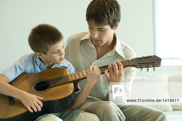 Vater und Sohn spielen zusammen Gitarre