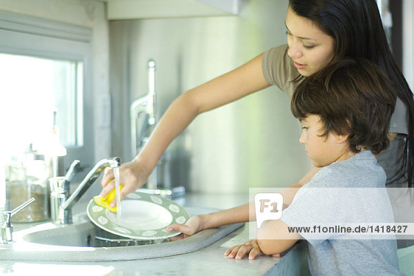 Mutter und Sohn beim Geschirrspülen