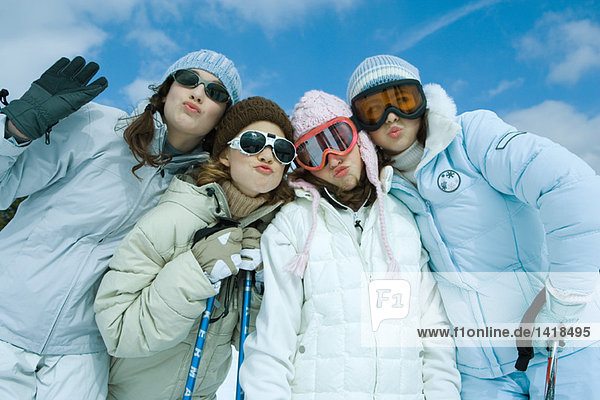 Four female friends dressed in ski clothing  puckering at camera  portrait