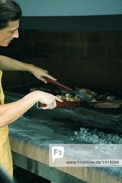 Mann beim Grillen von Fleisch auf dem Grill