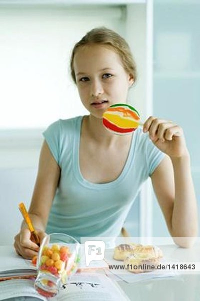 Mädchen essen Süßigkeiten und machen Hausaufgaben