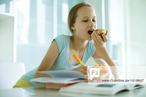 Mädchen essen süße Snacks und machen Hausaufgaben