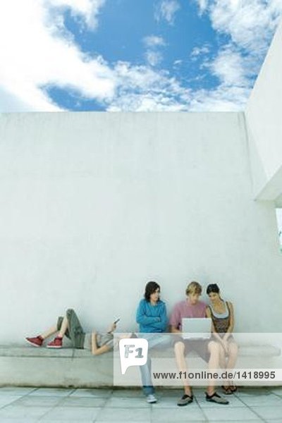 Junge Freunde  die im Freien sitzen  mit dem Laptop