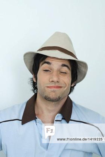Junger Mann mit Hut  Augenzwinkern vor der Kamera  Porträt