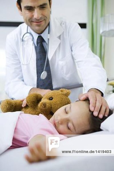 Arzt mit Hand auf schlafendem Kinderkopf  lächelnd