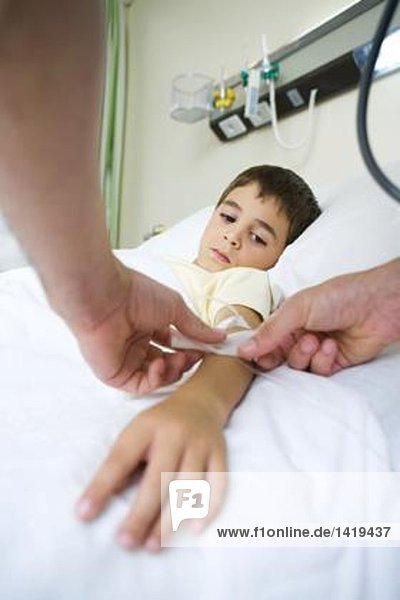 Junge im Krankenhausbett liegend  mit IV an den Arm geklebt