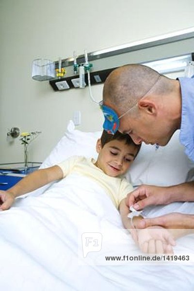 Boy lying in hospital bed  nurse adjusting IV