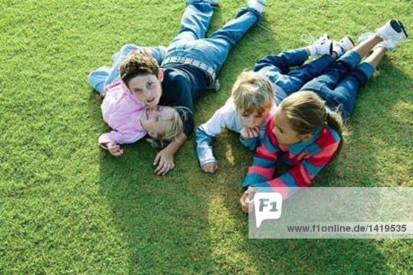 Kinder  die zusammen auf Gras liegen