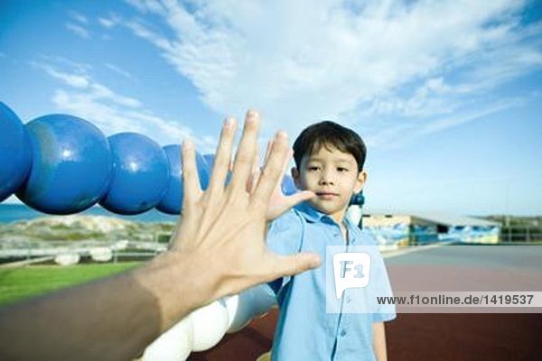 Junge auf dem Spielplatz  Hand in Hand mit der erwachsenen Hand haltend