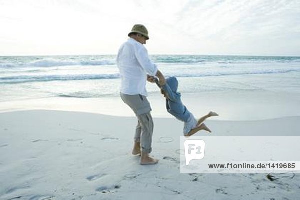Großvater schwingender Junge am Strand