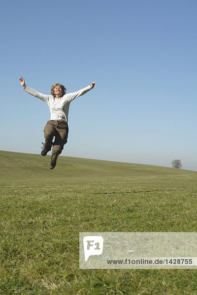 Woman jumping in meadow  arms up