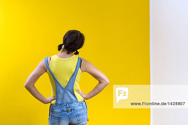 Woman standing in front of yellow wall  rear view