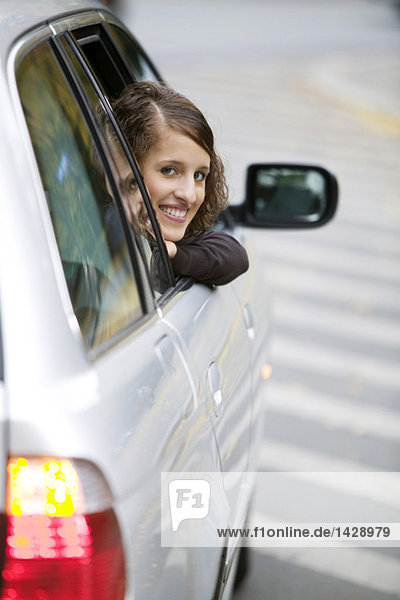 Junge Frau  die aus dem Auto schaut  lächelnd
