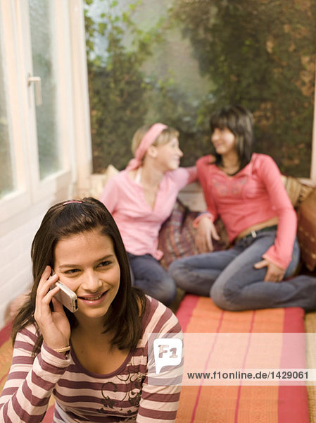 Girl (16-17) phoning  girl friends sitting in backgroud