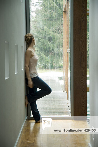 Woman in a hall looking out of window