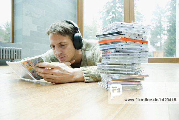 Mann mit Kopfhörern und CDs auf dem Boden liegend