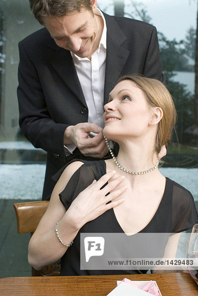 Mann befestigt Halskette am Frauenhals