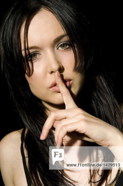 Dark-haired woman finger to mouth
