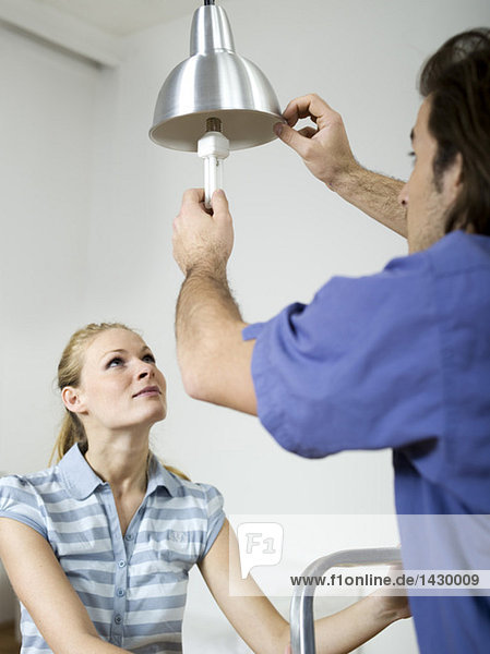 mna fixing bulb  woman holding ladder