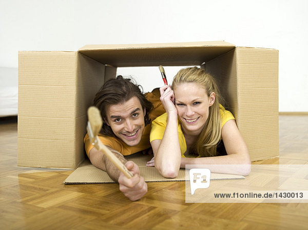 Couple lying in box  holding brushes
