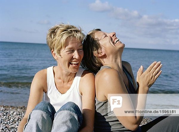 Two laughing women on a beach.