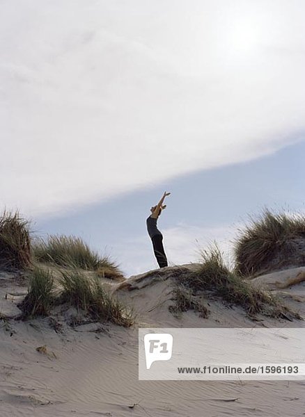 A woman stretching up against the sky.