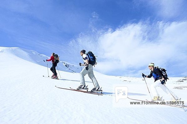 Drei Skifahrer der Skipiste Storulvan Jamtland Schweden hinauf.