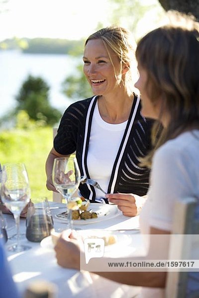 Zwei Frauen mit Mittagessen in einem Mittsommer feiern Fejan Stockholm Archipel Schweden.