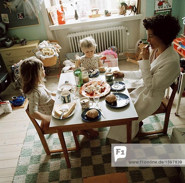 Mutter und Töchter essen Abendessen in einem Kind-Raum Schweden.