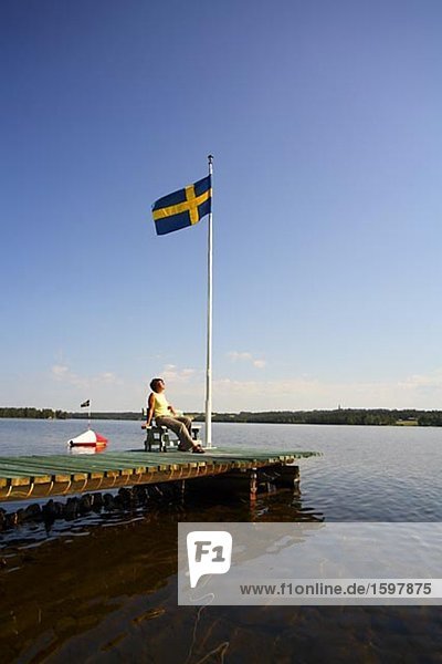 Skandinavischen Frau sitzt auf einer Bootssteg Jämtland Schweden.