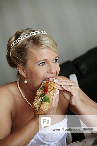 Eine Hochzeit gekleidet Frau isst einen Sandwich Schweden.