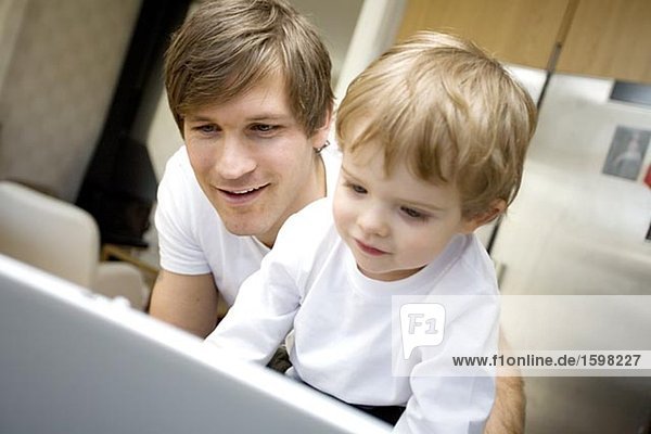 A father and a small child in front of a computer at home Sweden.