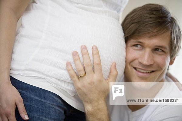 A man listening to a pregnant woman's stomach Sweden.