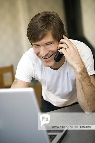 A smiling man with a laptop talking in the phone Sweden.