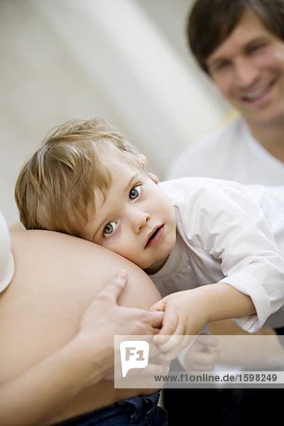 A small child listening to a pregnant woman's stomach Sweden.