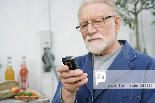 Ein älterer Mann mit einen Handy.