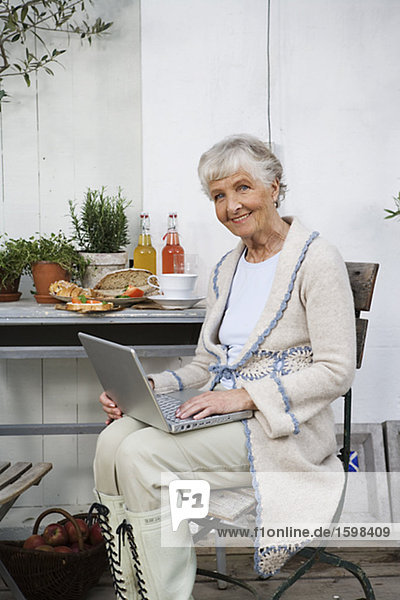 Eine ältere Frau Schreiben auf ihrem Computer Schweden.
