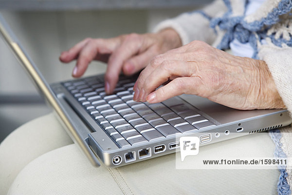 An elderly woman writing on her computer Sweden.