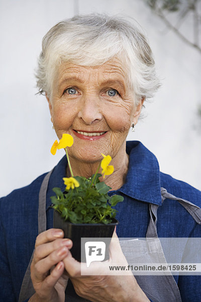 Eine ältere Frau hält eine Blume Schweden.