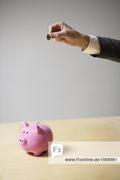 Ein Mann Einfügen von Geld in ein Sparschwein.