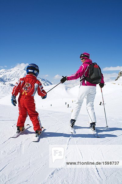 Eine Mutter und ihr Sohn Skifahren in den Alpen.