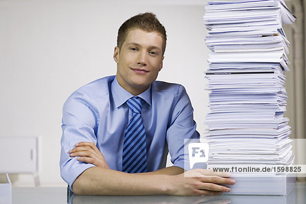 Ein Mann mit einem Haufen von Papier in einem Büro.