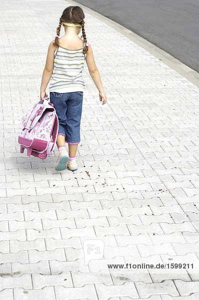 Rückansicht des Mädchen tragen Schultasche am Straßenrand
