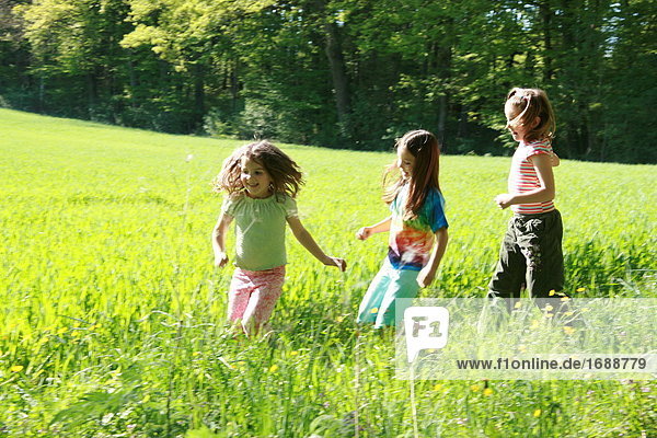 Three girls running in field